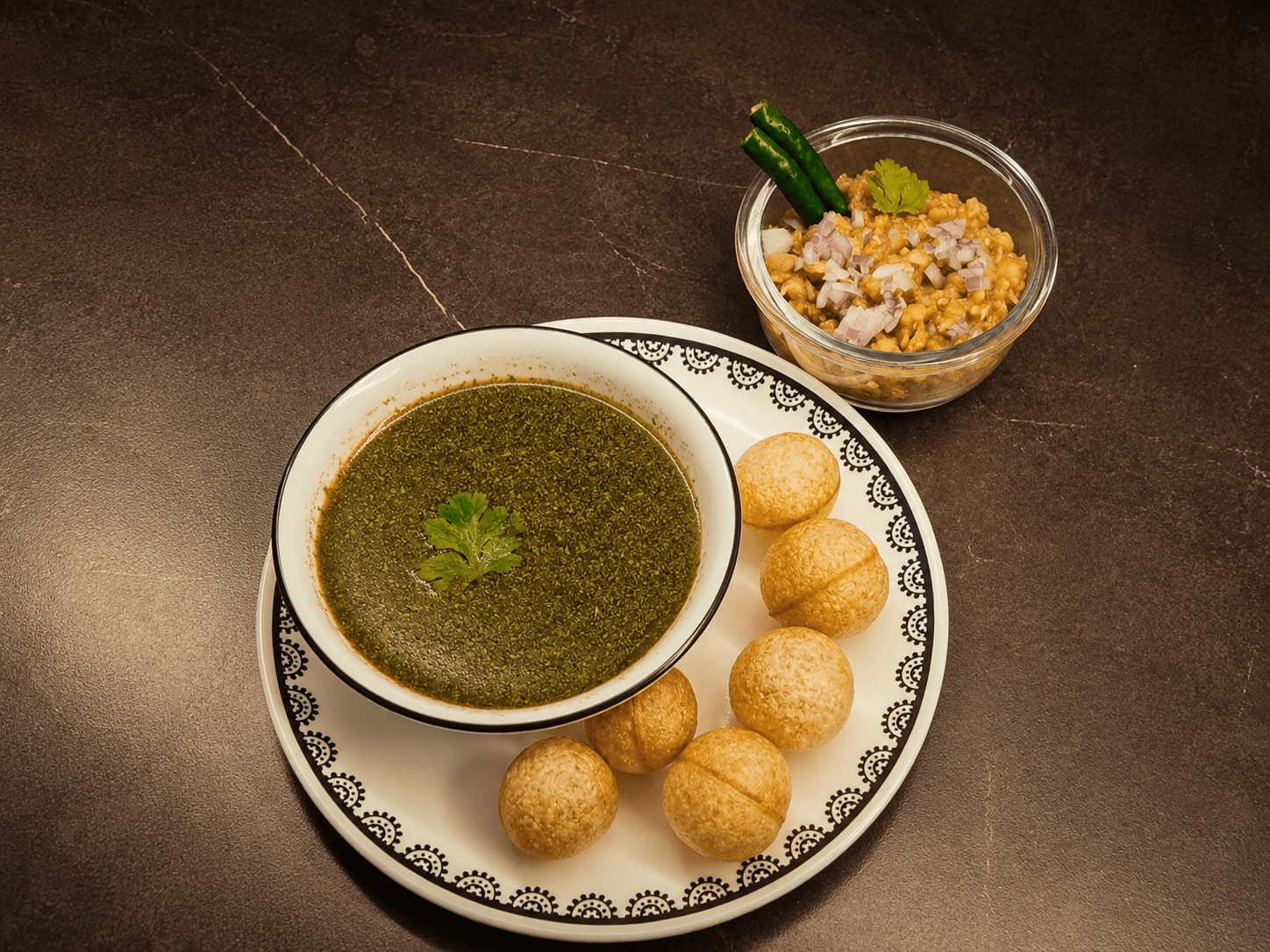 A bowl of chilled coriander-mint pani beside six crisp golden puris and a bowl of spiced potato-chickpea filling.
